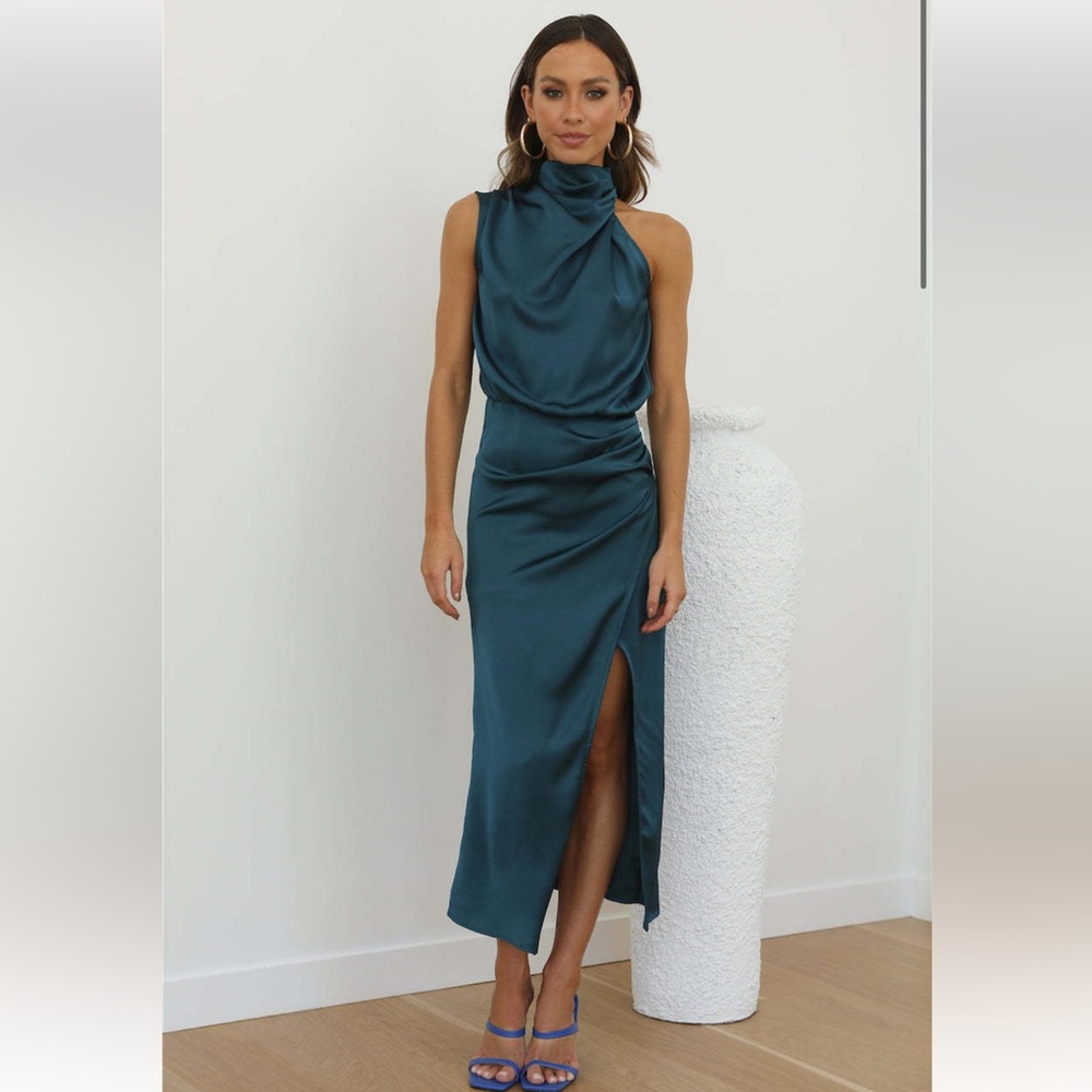 The Cocktail Party Midi Dress features a drape cowl neck design and side split.